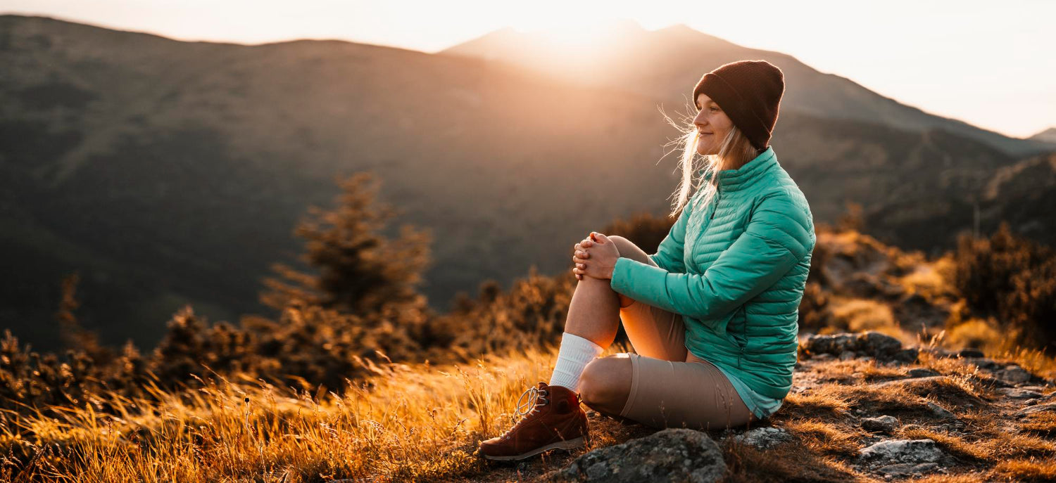 woman sitting on mountain at sunset